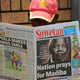 A man reads a newspaper bearing a photo offormer South African President Nelson Mandela. (Alexander Joe/AFP)